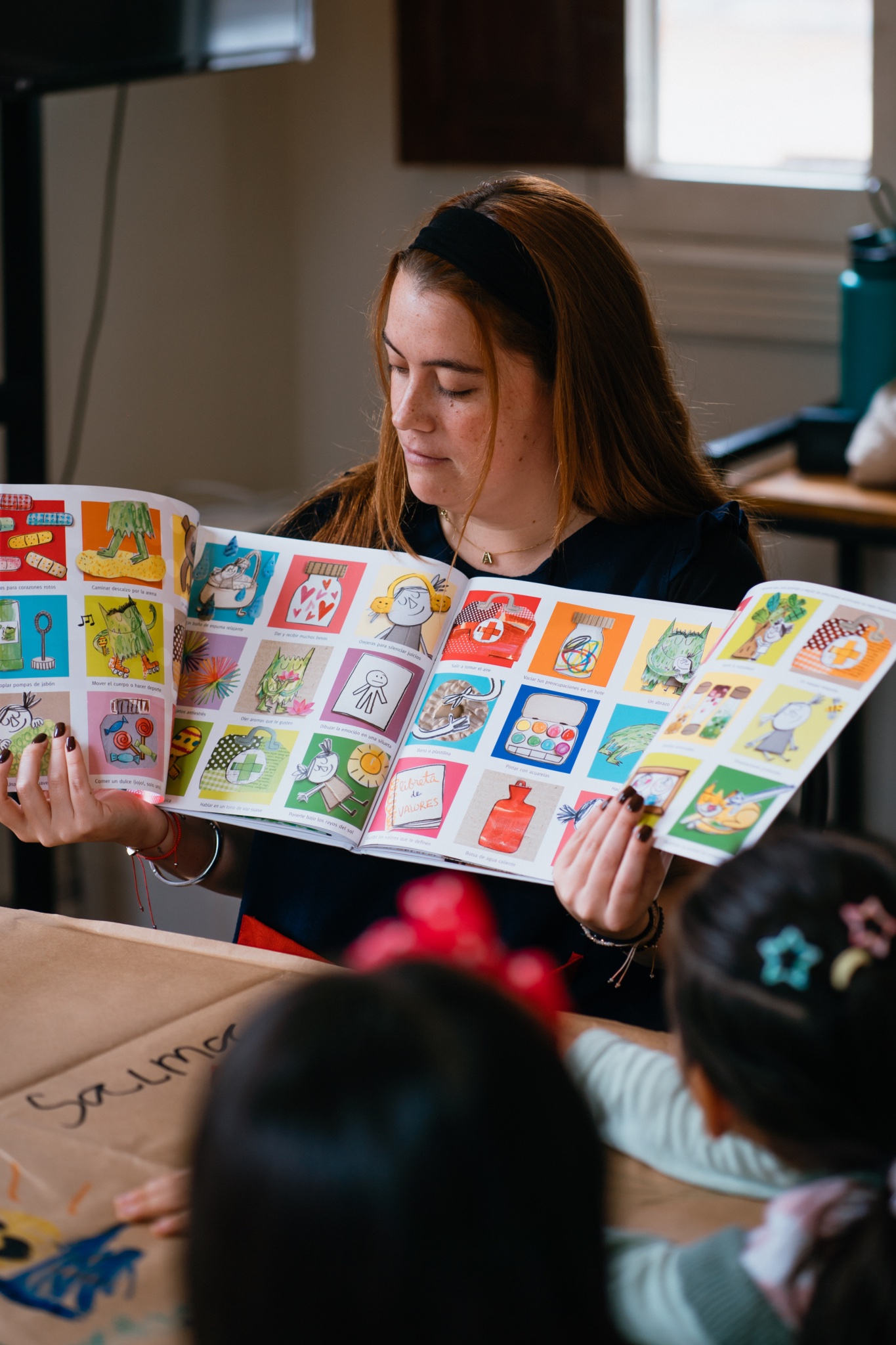 Miss leyendo un libro ilustrado a las niñas