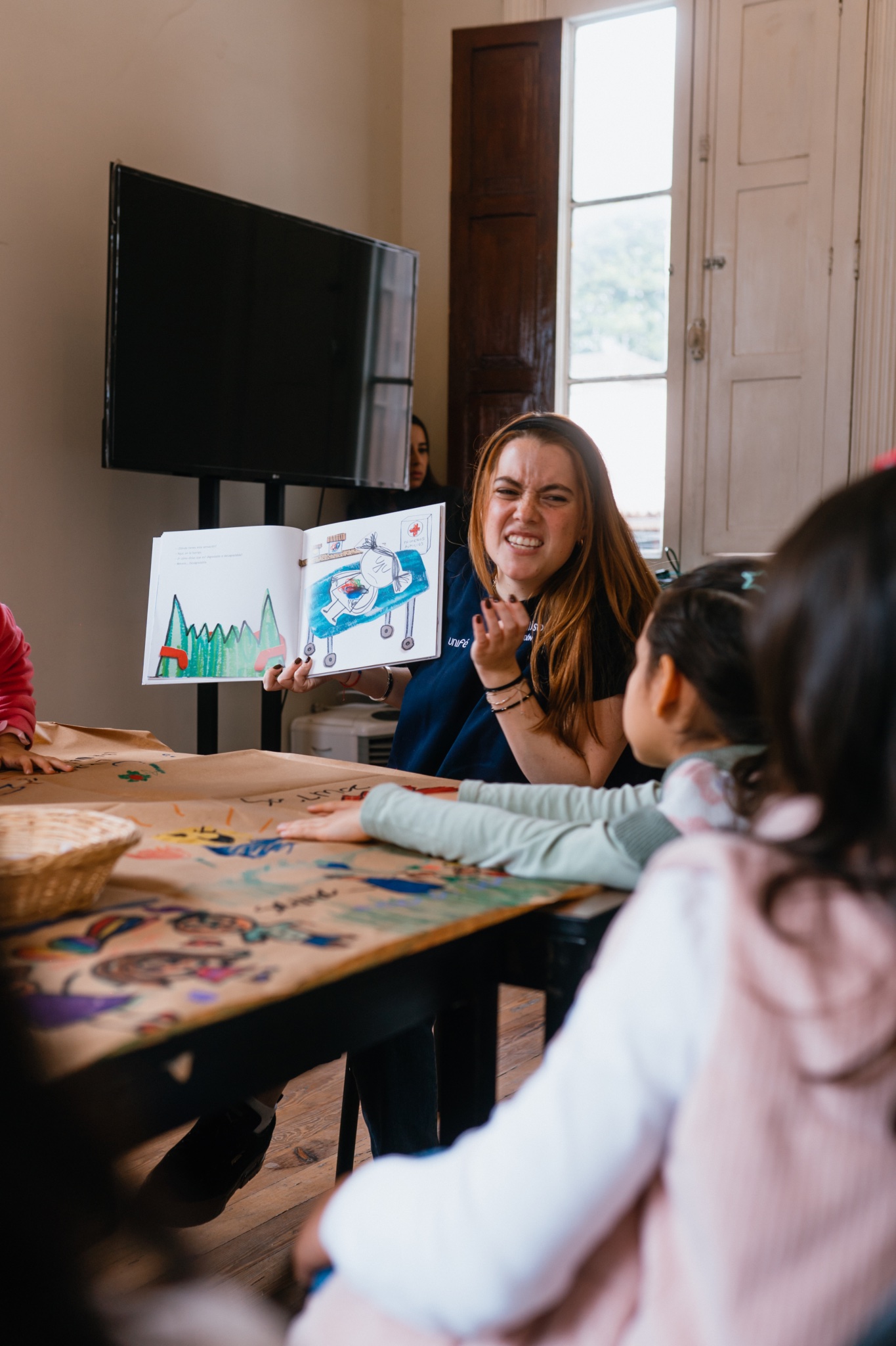 Miss mostrando un libro ilustrado a las niñas