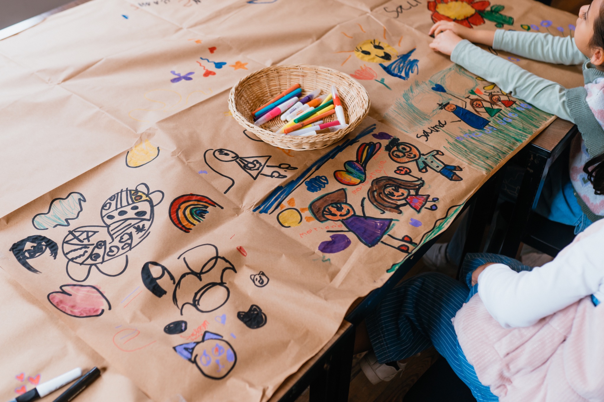 Mesa de arte con dibujos de niñas y marcadores de colores